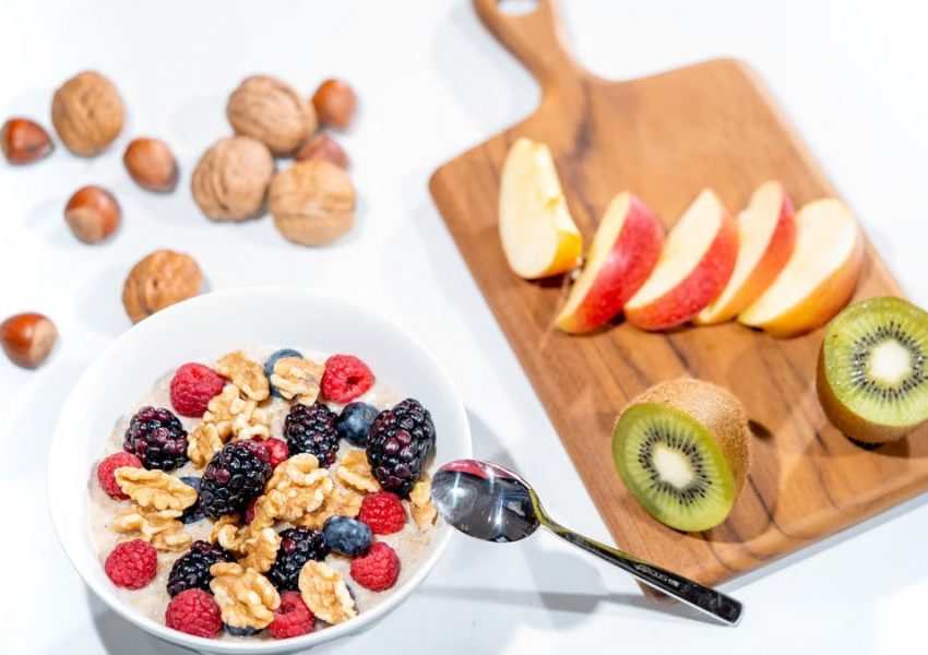 A nutritious breakfast bowl featuring fresh berries and walnuts, served with sliced fruit and kiwi.
